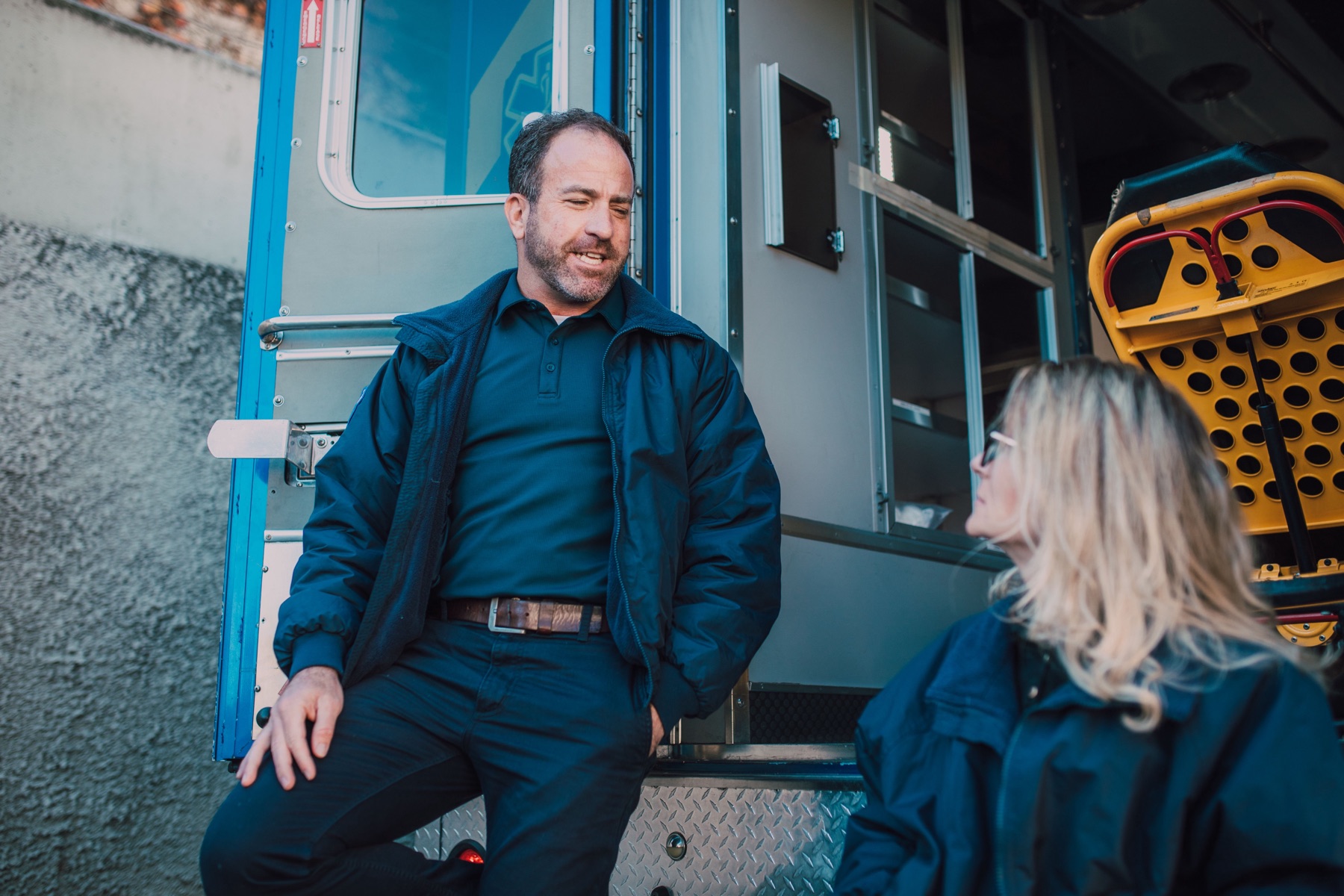 A paramedic speaking with a colleague beside an ambulance